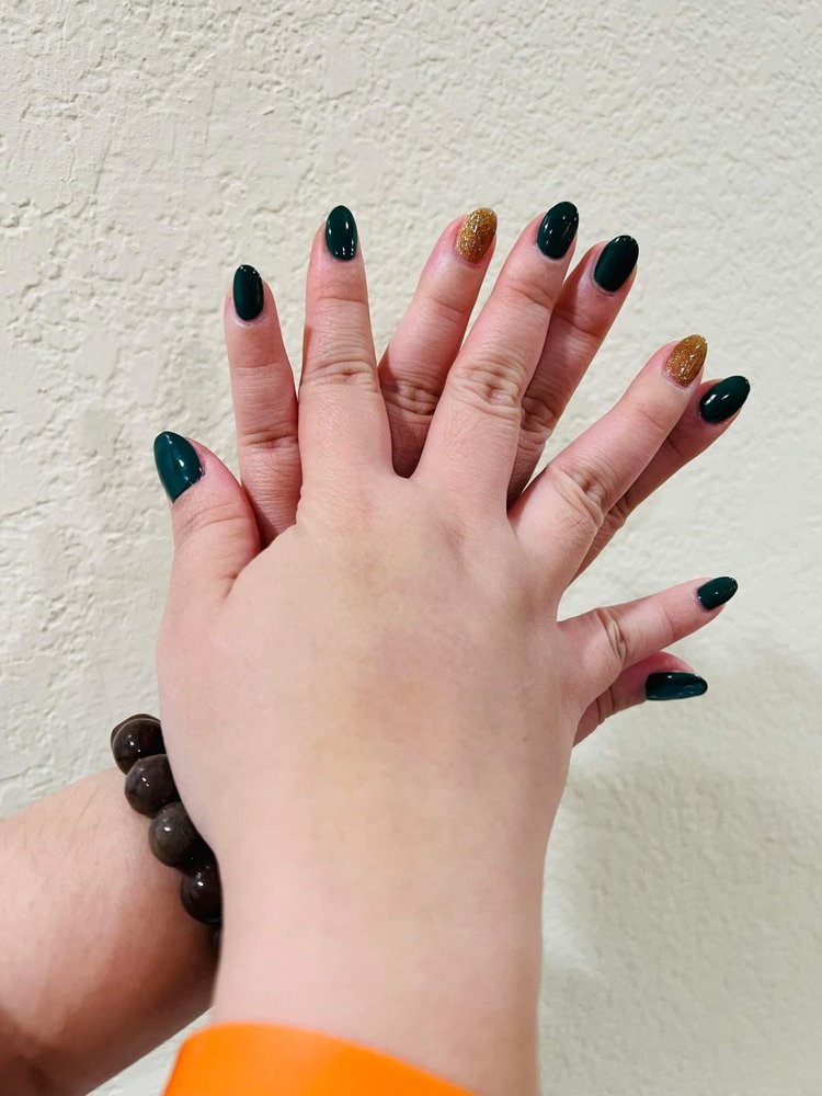 Short forest-green manicure with two gold glitter accents.