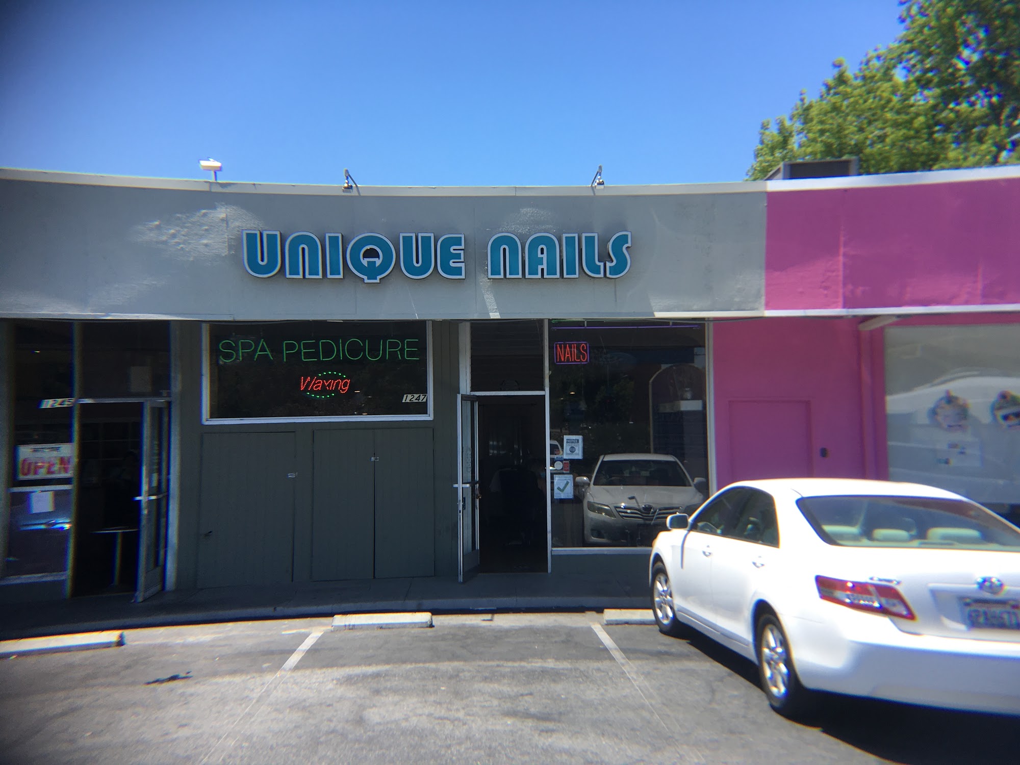 Unique Nails from the private lot — UNIQUE NAILS letters, SPA PEDICURE and Waxing neon, pink neighboring wall.