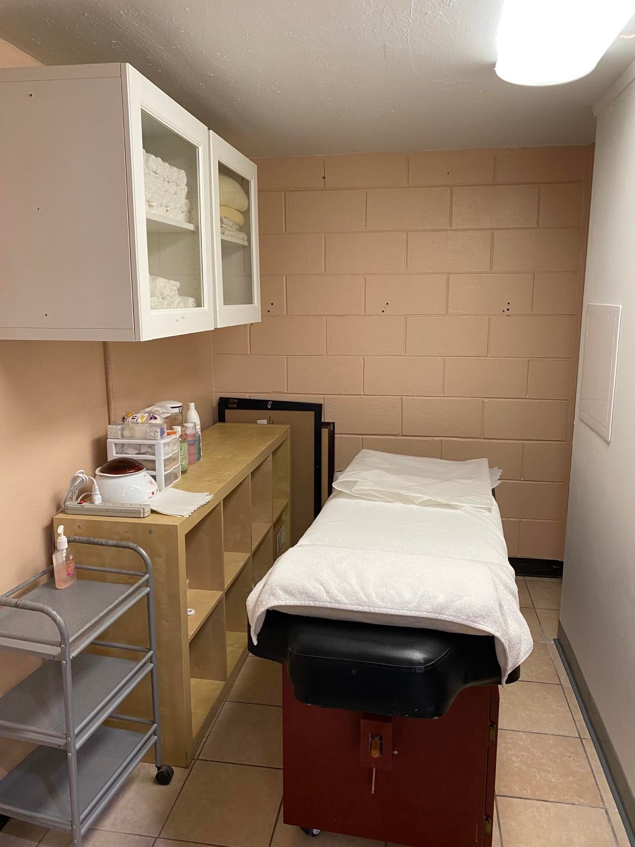 Wax and facial room: treatment table, towels, and a warmer.
